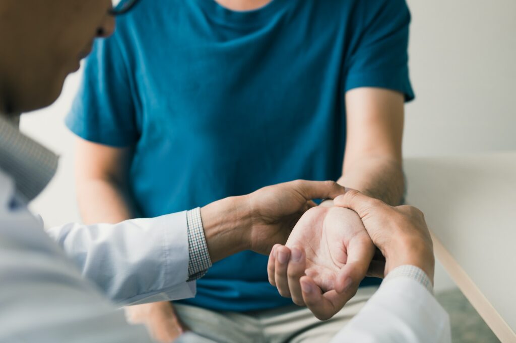 Physical therapist checks the patient wrist by pressing the wrist bone in clinic room.